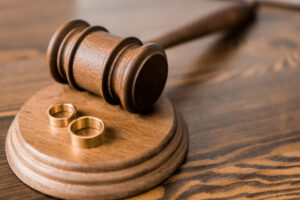 Divorce Lawyer Alpine, NJ - GAVEL ON WOODEN TABLE WITH GOLD WEDDING RING BANDS
