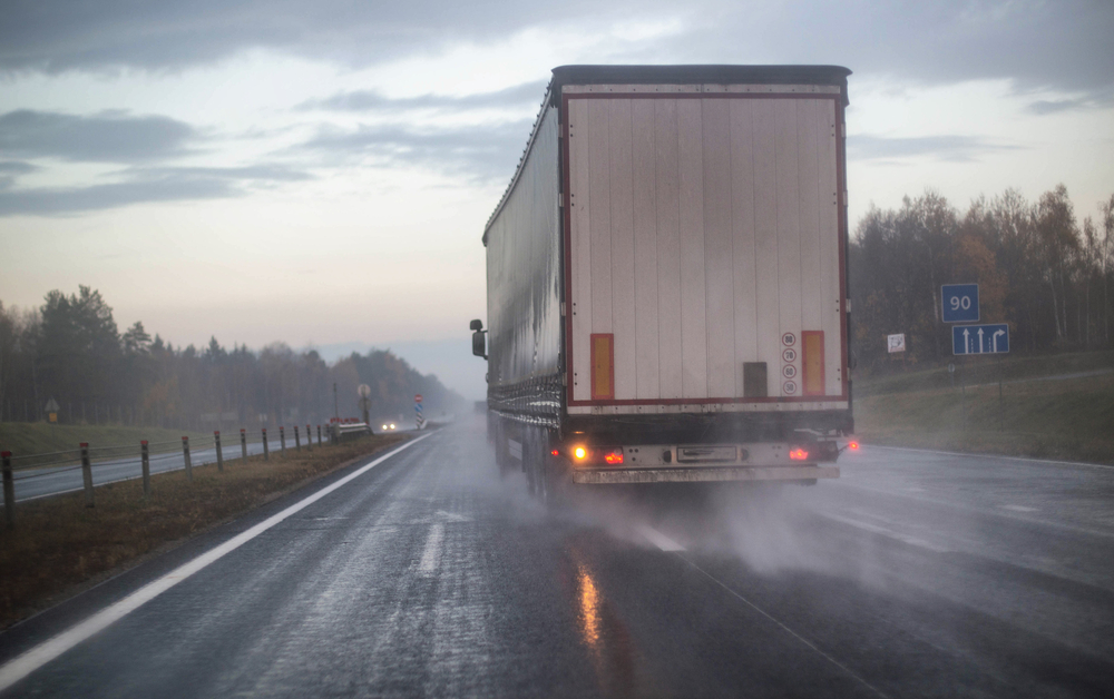 Trucking Lawyer Hackensack, NJ - A truck with a trailer is being rebuilt on a motorway in a different row on slippery wet roads. The concept of security and attention to roads in bad weather, rain